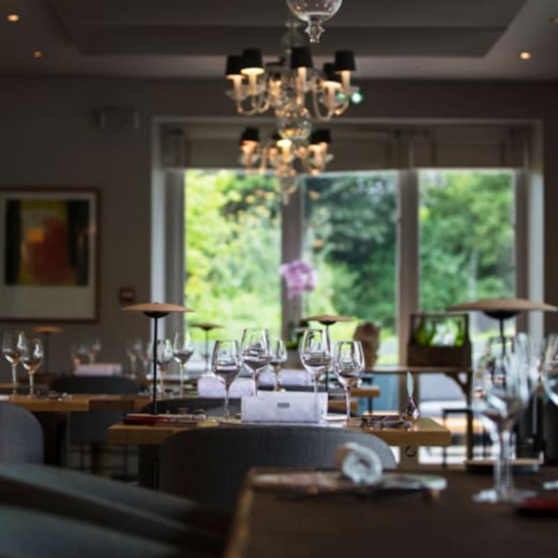 Une maison moderne avec une façade peinte dans des tons neutres élégants, reflétant l'architecture contemporaine française sous un ciel clair, avec une touche de verdure