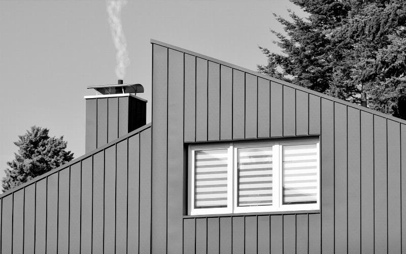 Application méticuleuse de peinture sur tôle galvanisée dans un atelier français, mettant en valeur le savoir-faire artisanal.