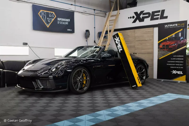 Alt text: Un carrossier appliquant de la peinture sur une zone réparée d'une voiture