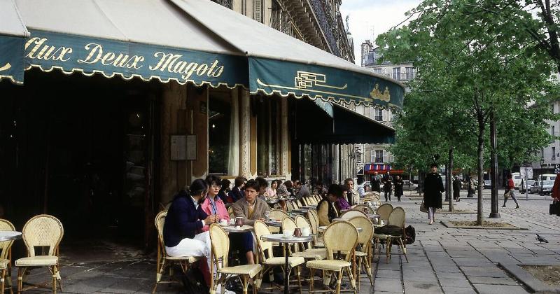 Des penseurs existentialistes français dans un café parisien avec des classiques littéraires
