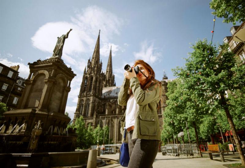 Vue animée de la Place de Jaude à Clermont-Ferrand avec des terrasses de restaurants, vie locale
