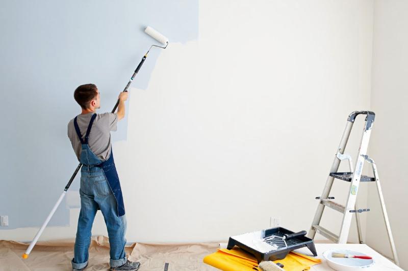 Préparation méticuleuse d'un mur abîmé avant application de peinture couvrante pour une finition parfaite