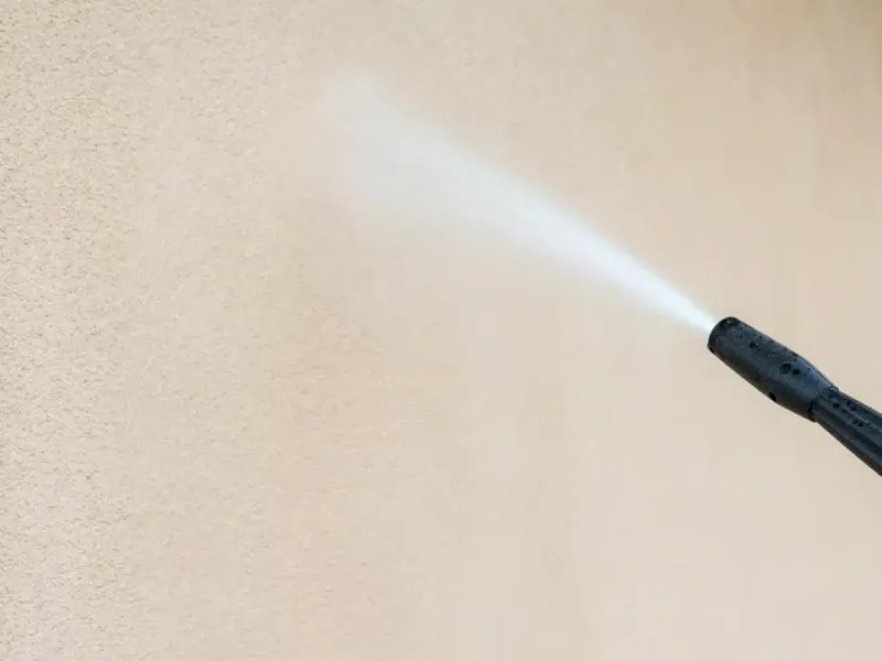 Nettoyage en profondeur d'un sol en béton extérieur avant peinture, montrant une brosse et un jet d'eau