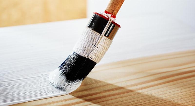 Un artisan prépare un mur en le ponçant légèrement avant d'appliquer une peinture laque mat