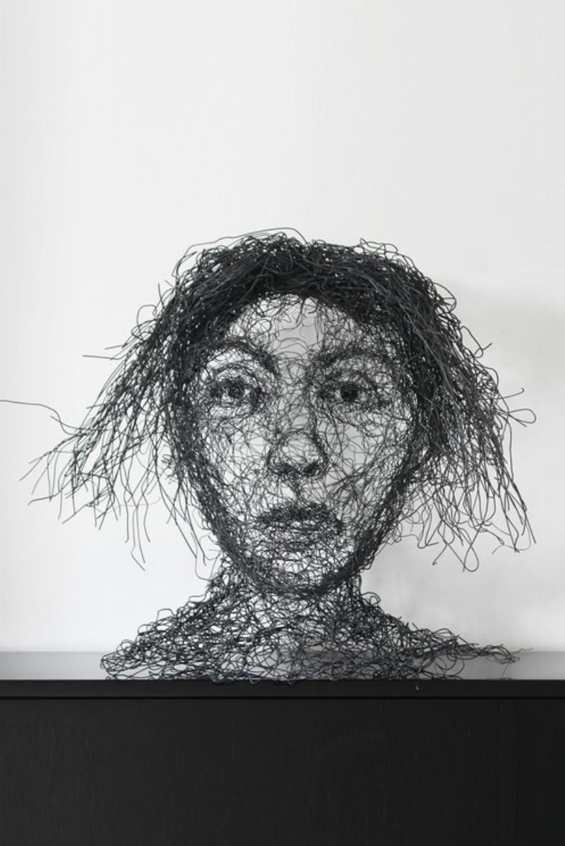 Sculpteur contemporain travaillant sur un portrait avec un regard intense