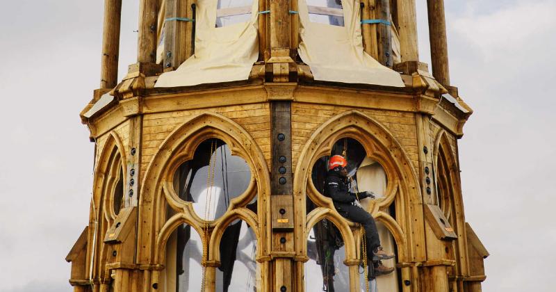La reconstruction de Notre Dame de Paris, avec des échafaudages recouvrant la structure et des artisans au travail.