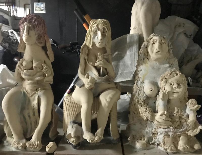 Un sculpteur concentré travaillant sur une statue tête de mort géante dans son atelier d'art, outils à la main