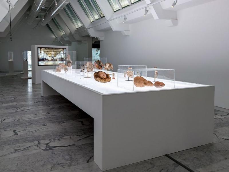 Visiteur contemple sculpture moderne corps femme argile, galerie contemporaine lumineuse