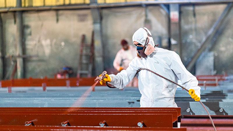Opérateur équipé de protections respiratoires travaillant dans cabine de peinture