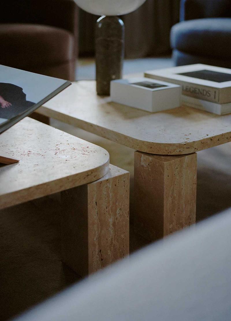 Une grande statue design salon abstraite en pierre blanche, servant de point focal dans un salon spacieux et lumineux avec des baies vitrées.