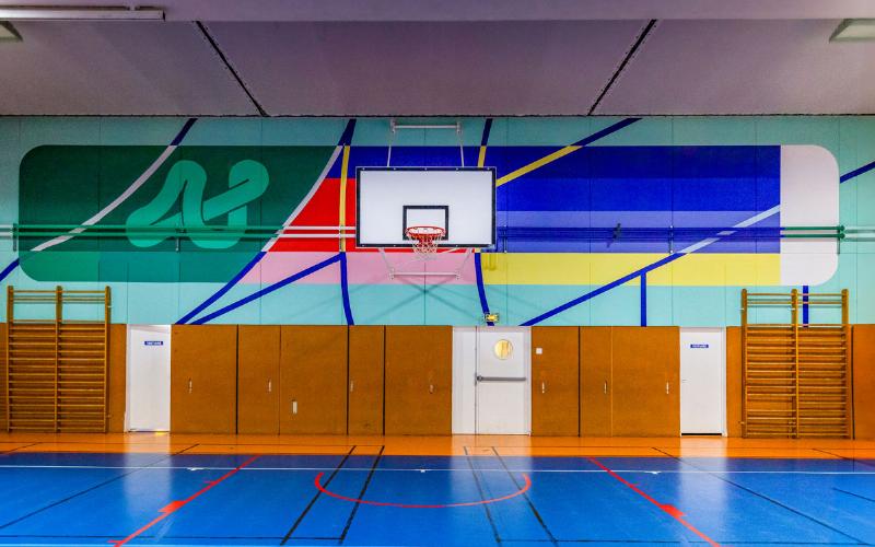 Une fresque de street art vibrante dans une rue parisienne en 2022, représentant des motifs abstraits et des figures humaines stylisées, illuminant le paysage urbain.