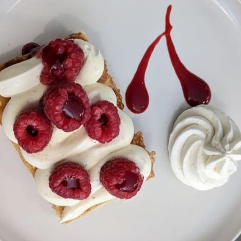 Table dressée en extérieur dans un restaurant Tournefeuille avec assiettes, verres, et fleurs