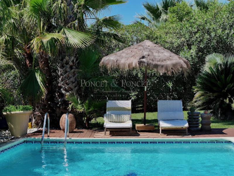 Terrasse spacieuse d'une maison d'architecture moderne avec vue panoramique sur un paysage verdoyant et un ciel bleu clair