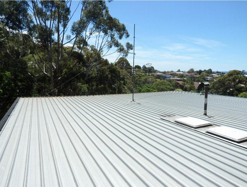 Application professionnelle d'une peinture cool roof sur une toiture métallique moderne