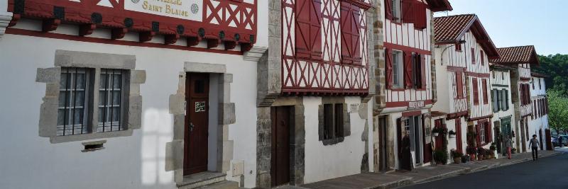 Maison basque traditionnelle en pierre avec colombages en bois, paysage verdoyant.
