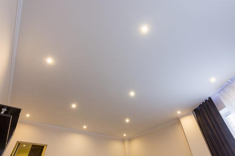 Alt text: Main tenant un rouleau appliquant de la peinture blanche professionnelle sur un mur intérieur bien préparé.