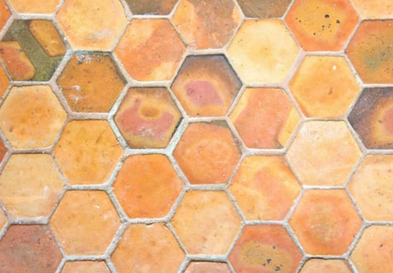 Application méticuleuse de la peinture sur les tomettes rouges