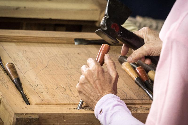 Artisan sculpteur travaillant le bois dans son atelier, entouré d'outils et d'œuvres en cours