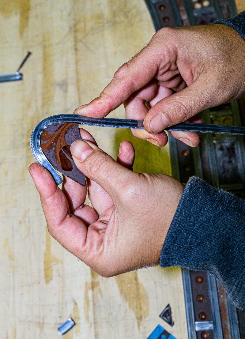 Artisan travaillant sur une pièce de verre peint dans un atelier français