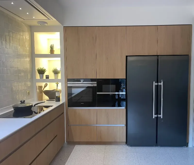 Cuisine moderne minimaliste avec des armoires en bois clair, un îlot central épuré et un éclairage doux