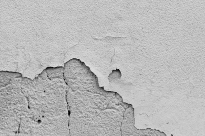 Application d'un décapant chimique sur une terrasse en béton extérieur pour enlever une ancienne peinture écaillée