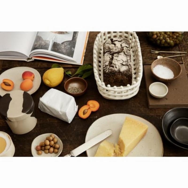 Une composition de détails décoratifs dans une palette marron glacé : bougies, poteries, livres et un vase en verre dépoli, sur une table en bois patiné.