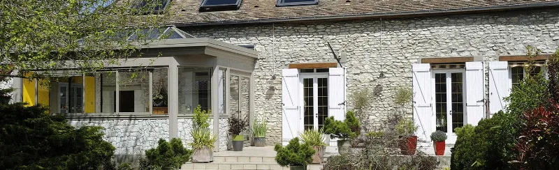 Exemple d'extension de maison française combinant pierre ancienne et bardage bois moderne