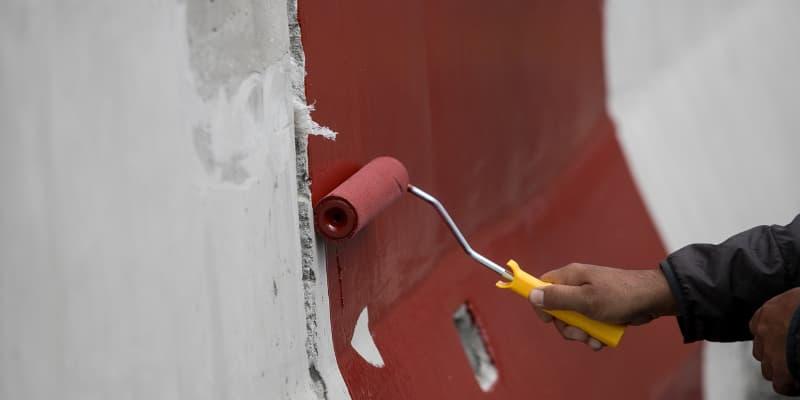 Homme préparant un sol en béton avant de le peindre, nettoyage et ponçage, étape essentielle pour la peinture sol intérieur maison.