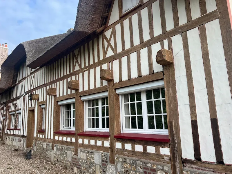 Restauration d'une façade Tudor en France, mélangeant pierre et colombage