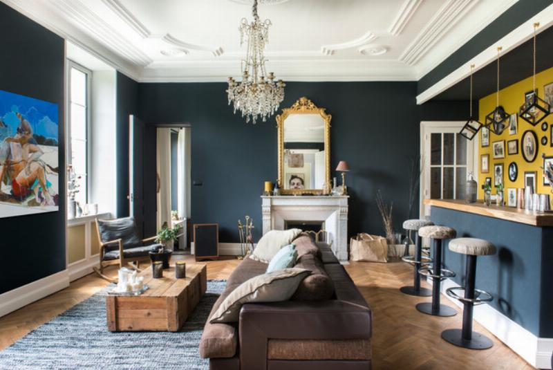 Salon contemporain avec murs peints en gris anthracite RAL 7016, contrastant avec un canapé clair et des accents dorés. Style décoratif français moderne.