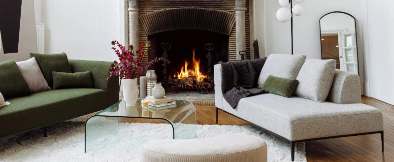 Un salon moderne et élégant aux murs peints en marron glacé, avec un canapé en velours crème, des meubles en bois foncé et des touches dorées, évoquant le style parisien.