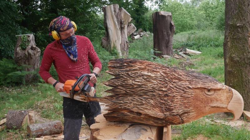 Artiste réalisant une sculpture sur bois à la tronçonneuse lors d'un événement public