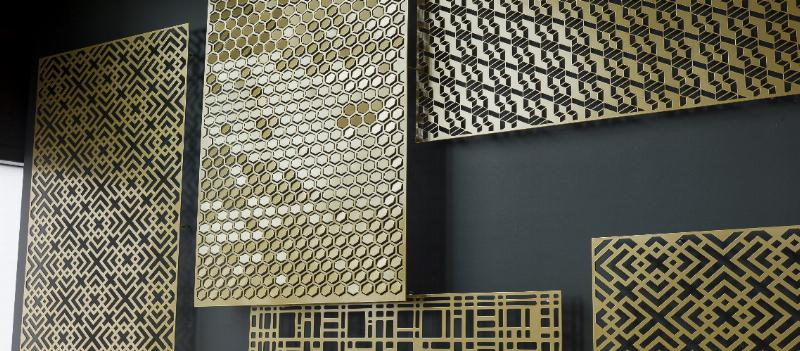 Sculpture murale design abstraite en métal brossé, formes géométriques entrelacées, lumière douce créant des ombres dynamiques sur un mur gris anthracite