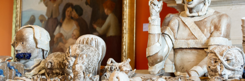 Statue de loup majestueuse grandeur nature en bronze, patine verte, regardant au loin, jardin luxuriant en arrière-plan.