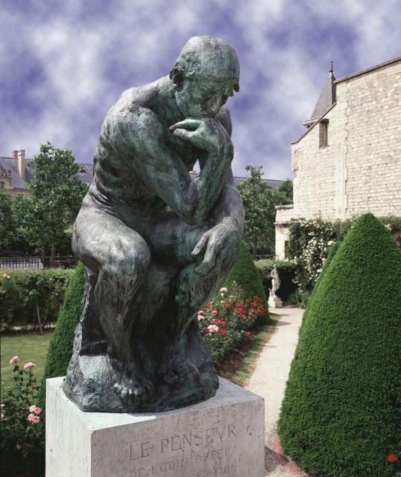 La statue du Penseur de Rodin, symbole universel de la philosophie et de la réflexion humaine, dans un jardin.