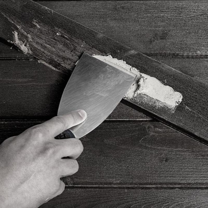 Artisan appliquant de la peinture sur une façade en utilisant un rouleau et un pinceau dans un style français traditionnel.